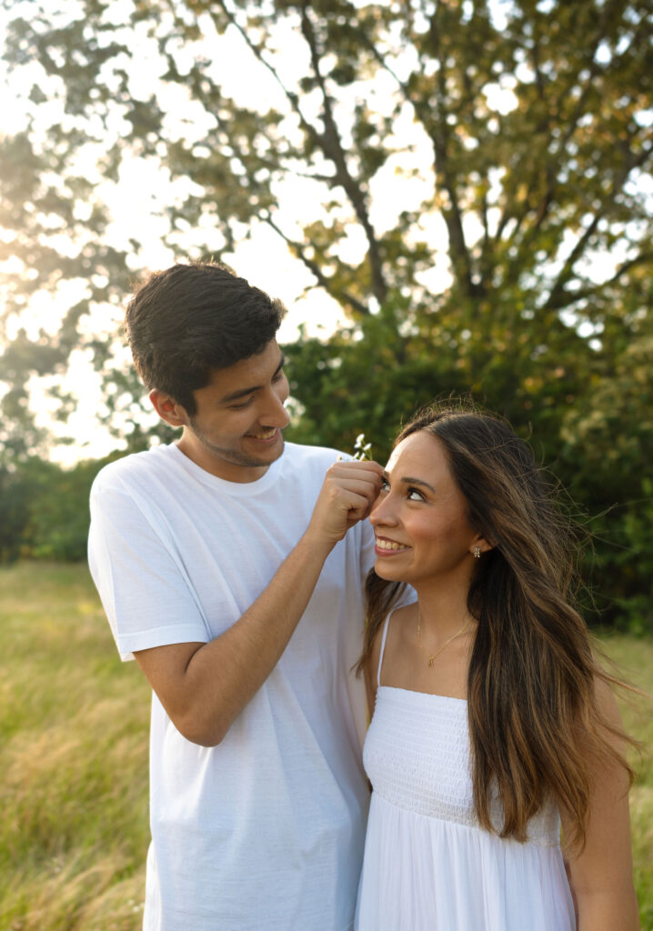 couple putting flowers behind ear arkansas engagement photos