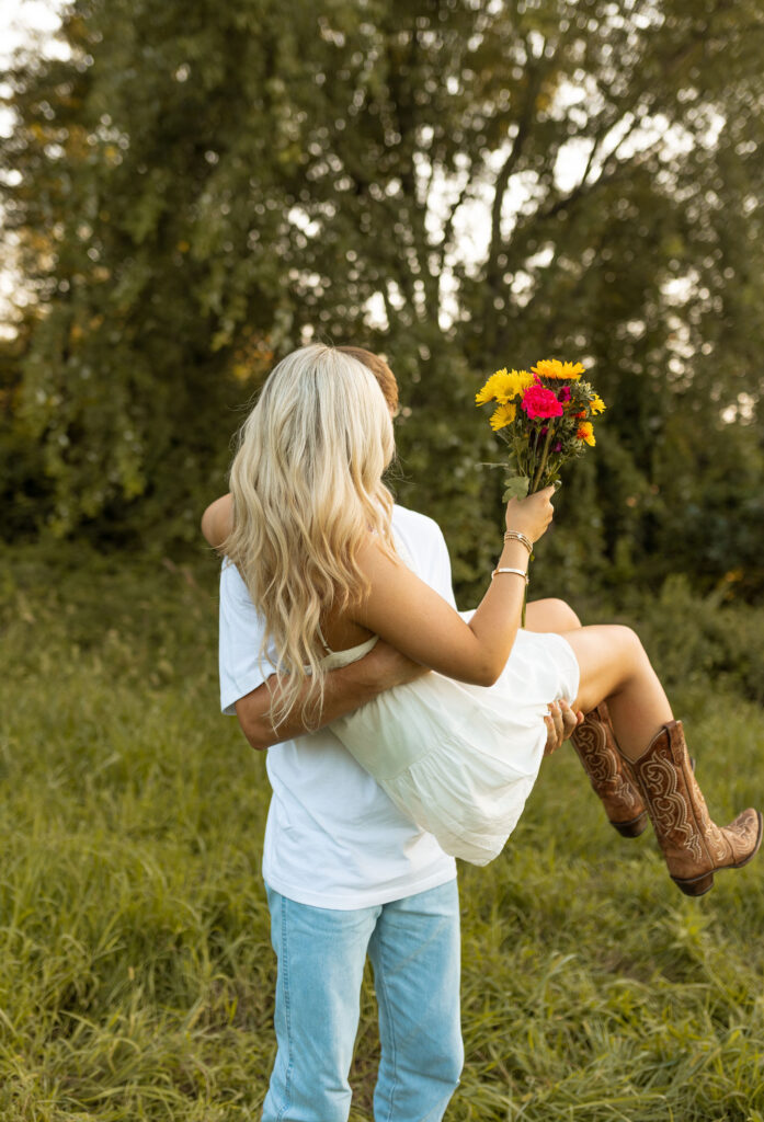 romantic couples poses with cowboy boots in a field